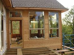 a house being built in the woods with windows on each side and wooden steps leading up to it