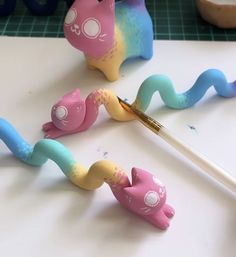 three toy animals sitting on top of a table next to a paintbrush and pencil