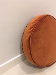 an orange round pillow on the wall