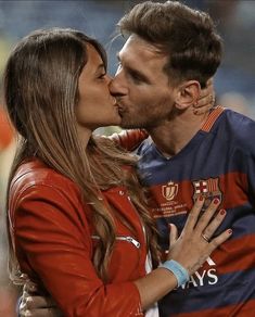 a man and woman kissing each other at a soccer game