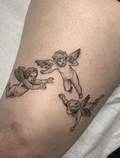 a tattoo with two cherubs and one angel on the side of a woman's leg