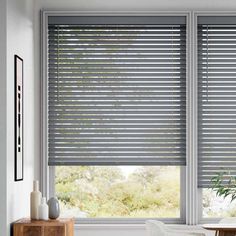 a living room with white walls and large windows covered in shades of grey blinds that are open to the outside