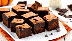 chocolate brownies with peanut butter frosting on a white plate next to a glass of milk