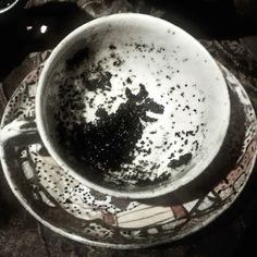 a dirty coffee cup sitting on top of a saucer with black stuff in it