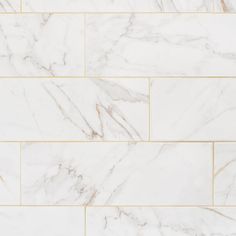 a white marble tile wall with gold trim