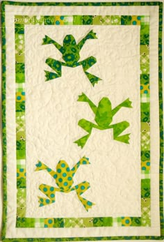 a quilted wall hanging with green frogs on it