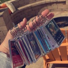 a person holding up several different types of cd's in front of a fire pit