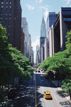 a yellow taxi cab driving down a street next to tall buildings in new york city