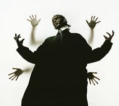 the silhouette of a person with their hands up in front of them, against a white background