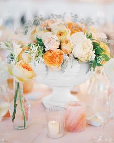 a white vase filled with lots of flowers sitting on top of a table next to candles