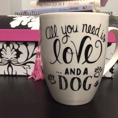 a white coffee cup sitting on top of a table next to books and a pink box