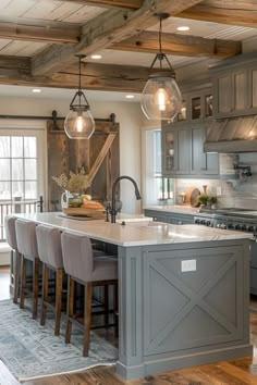 a large kitchen with gray cabinets and wooden beams on the ceiling, along with bar stools