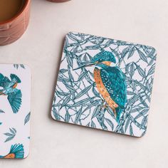 a blue and orange bird sitting on top of a coaster