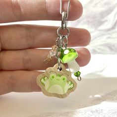 a hand holding a keychain with a green frog on it