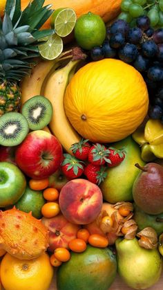 many different types of fruit are arranged together on a table with pineapples, bananas, oranges, kiwis and other fruits