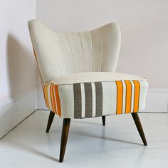 an upholstered chair with stripes on the seat and back rests against a white wall