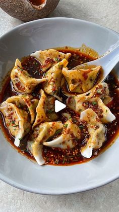 a white plate topped with dumplings covered in sauce