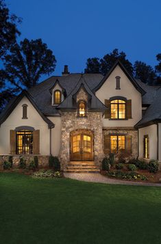 a large house with stone and wood trimmings in the front yard at night