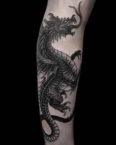 a black and white dragon tattoo on the leg