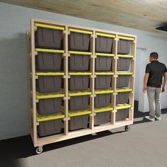 a man standing next to a shelf filled with bins