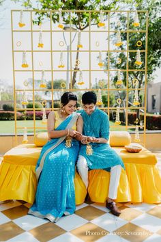 a man and woman sitting on top of a yellow table