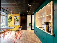 the interior of a modern office with wood flooring and green walls, colorful bar stools