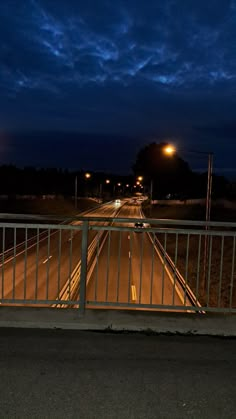 an empty street at night with the lights on and no cars driving down the road