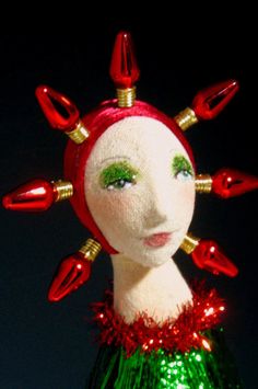 a doll is dressed in green and red with gold spikes on it's head