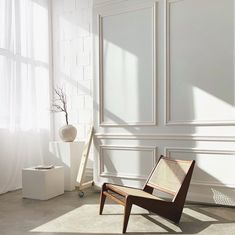 a chair sitting in front of a window next to a vase