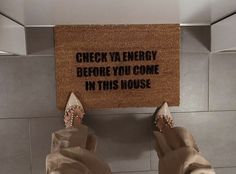 someone is standing in front of a door mat that says check ya energy before you come in this house