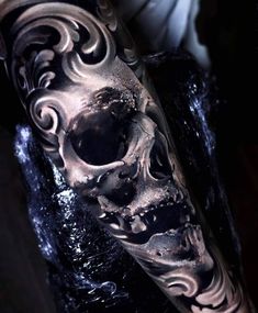 a man's arm with a black and white tattoo design on it, in the shape of a skull