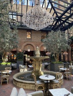 the inside of a restaurant with tables, chairs and a fountain in the center surrounded by trees