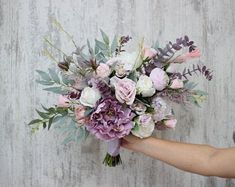 a woman holding a bouquet of flowers in her hand on a wooden background with planks