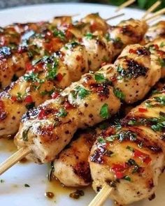 some chicken skewers are sitting on a white plate