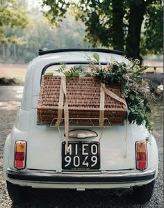 a white car with a basket on the back of it's trunk and flowers