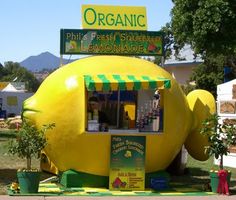 a large yellow lemonade stand on the side of a road