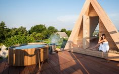 a woman sitting on top of a wooden structure next to a hot tub