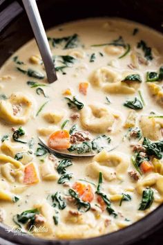 a ladle full of pasta and spinach soup with meat in a crock pot