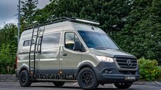 a mercedes benz van parked in a parking lot with trees and bushes behind it on a cloudy day