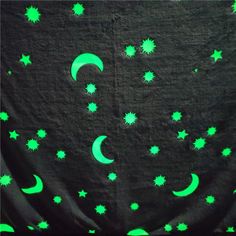 green stars and crescents glow in the night sky on a black background with white dots