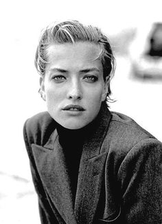 a black and white photo of a woman with short hair wearing a jacket looking at the camera