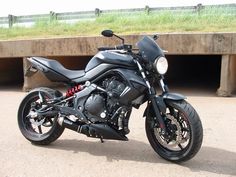 a black motorcycle parked in front of a concrete wall