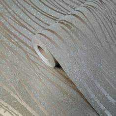 a roll of silver glitter paper sitting on top of a floor next to a wall