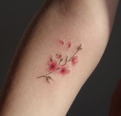 a woman's arm with pink flowers and leaves on the back of her leg