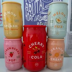 four different flavored cups sitting on top of a counter next to a sign that says cherry cola