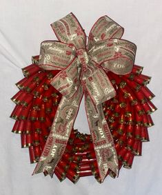 a red and gold christmas wreath on a white background with silver ribbon tied around it