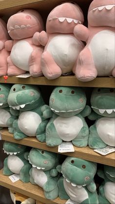 there are many stuffed animals on the shelves in this store, and one is pink and green