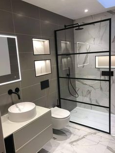 a bathroom with a glass shower door, toilet and sink in the middle of it