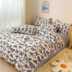 a bed with butterflies on it in a bedroom next to a white dresser and window