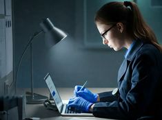 a woman in blue gloves working on a laptop